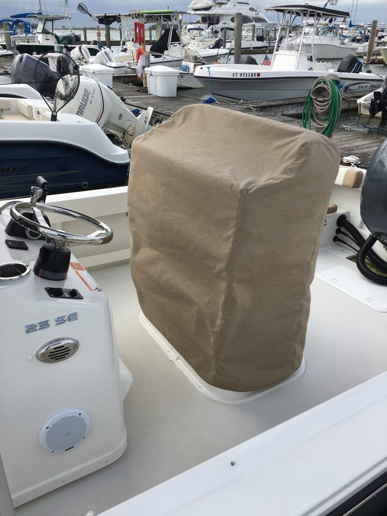 A boat with a cover on the steering wheel is docked at a marina.