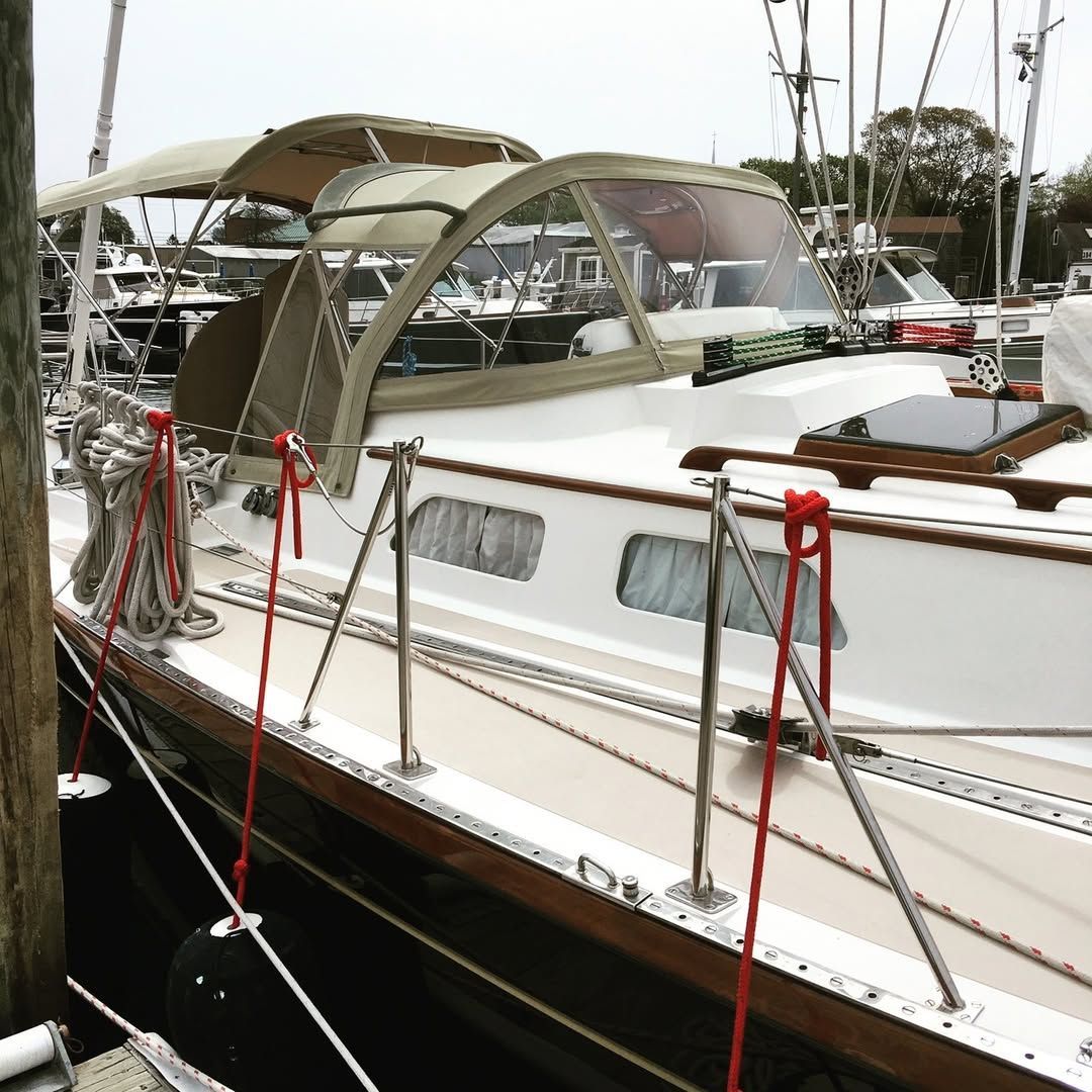 A sailboat with a canopy is docked at a marina