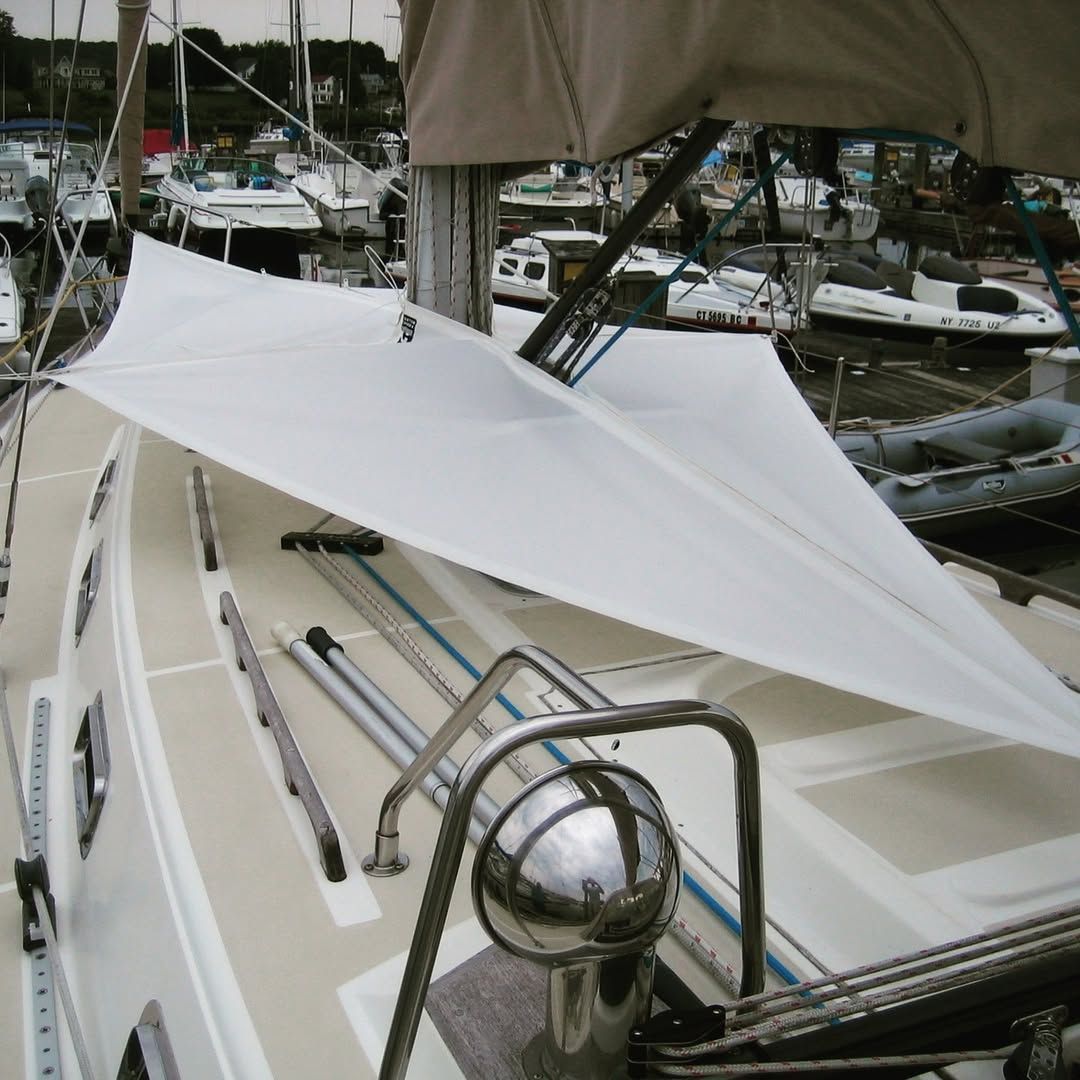 A boat with a white sail is docked in a marina