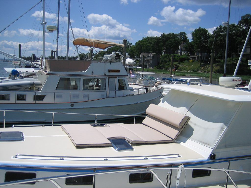 A boat with a cushion on the deck is docked in a marina