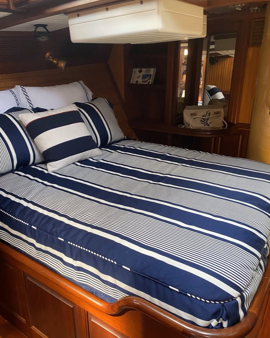 A bed with striped sheets and pillows on a boat