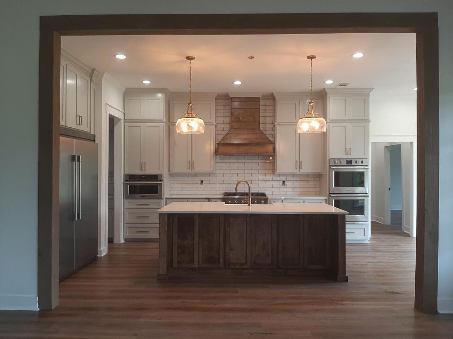Kitchen with white cabinets, wood island, and a wood range hood.