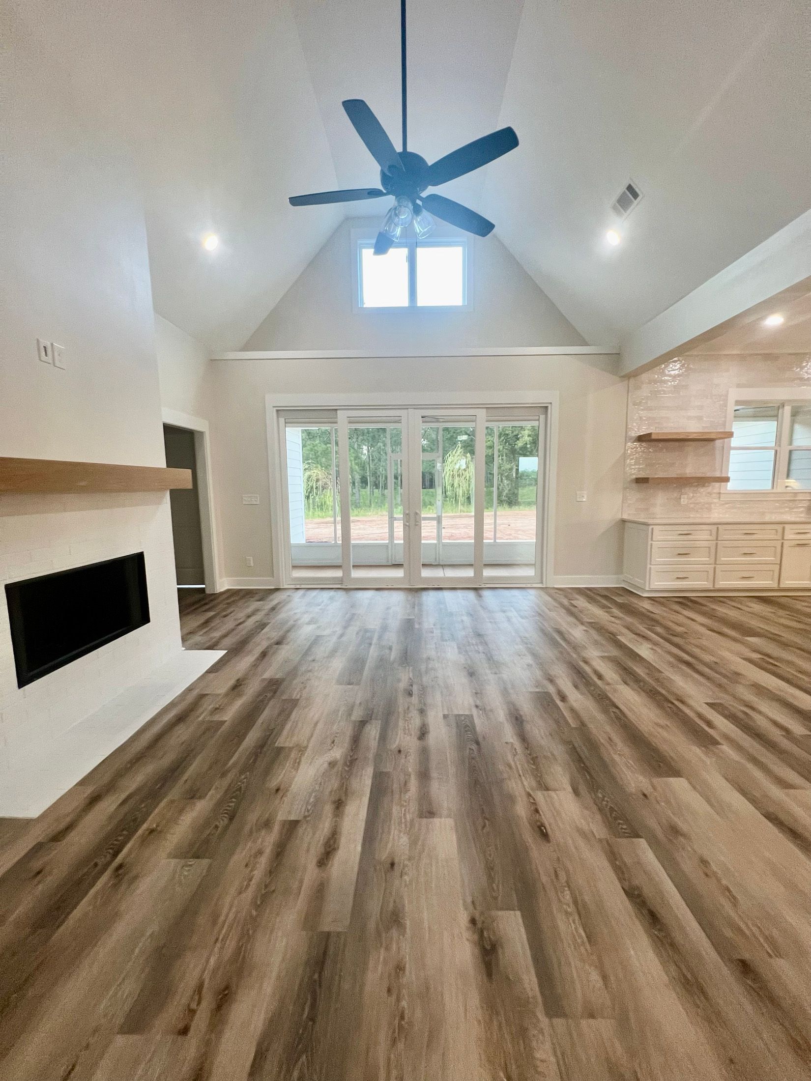 Spacious living room with wood floors, fireplace, and sliding glass doors leading to the outdoors.