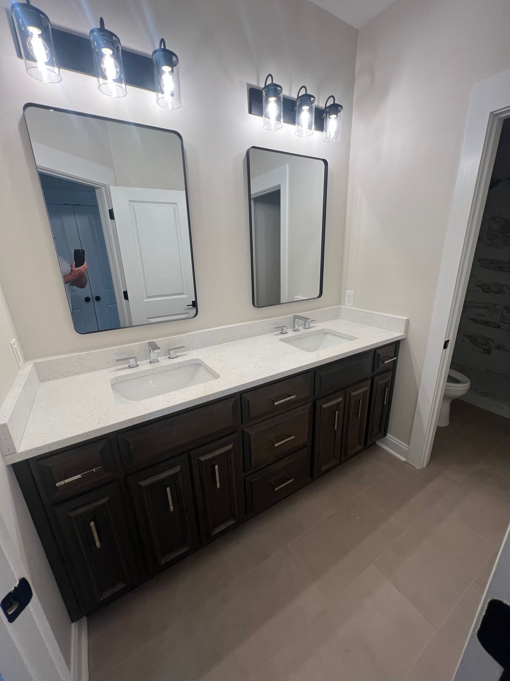 Bathroom with dark wood vanity, white countertop, two mirrors, and overhead lighting.