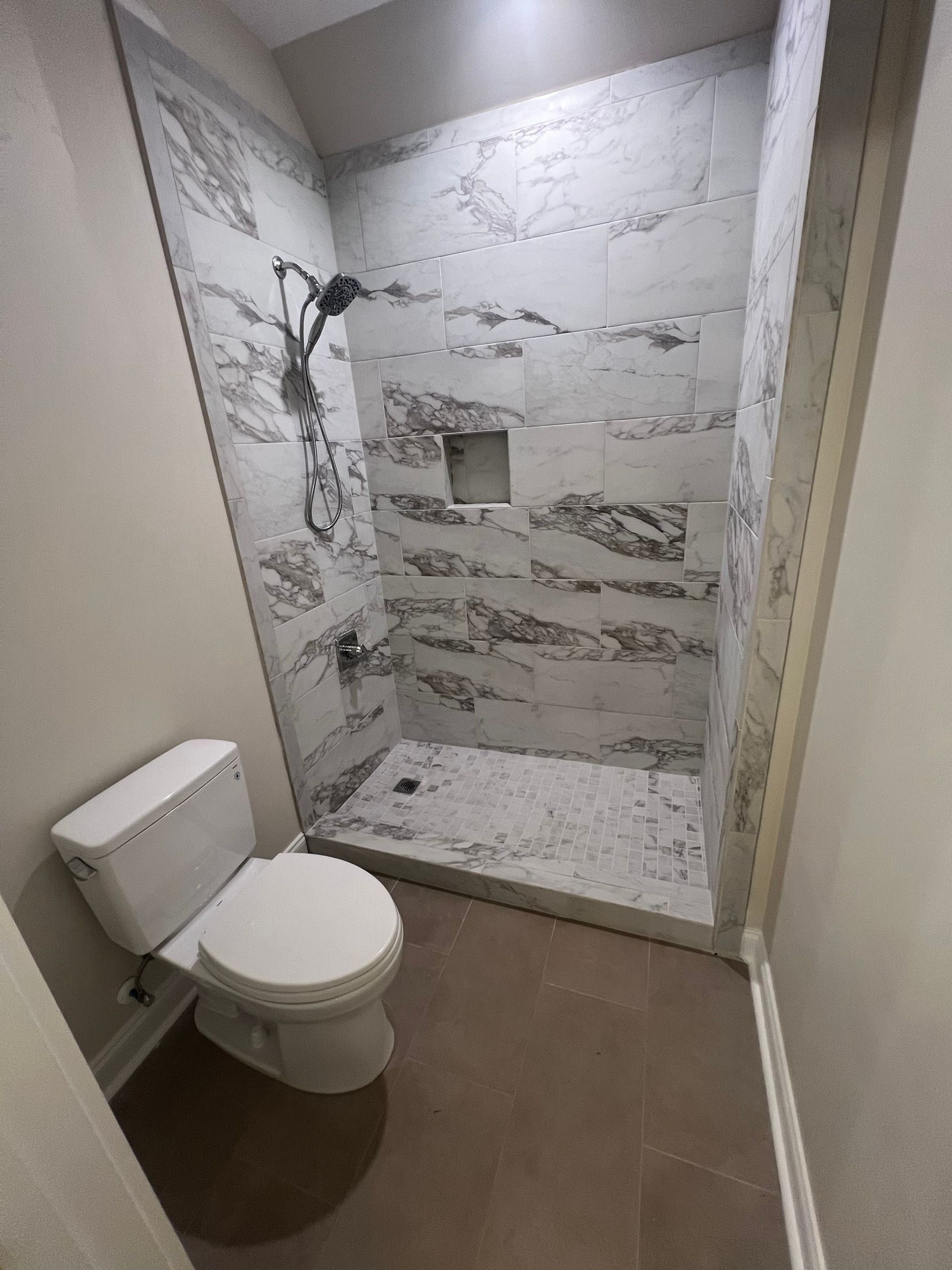 Small bathroom with a toilet and tiled shower stall.