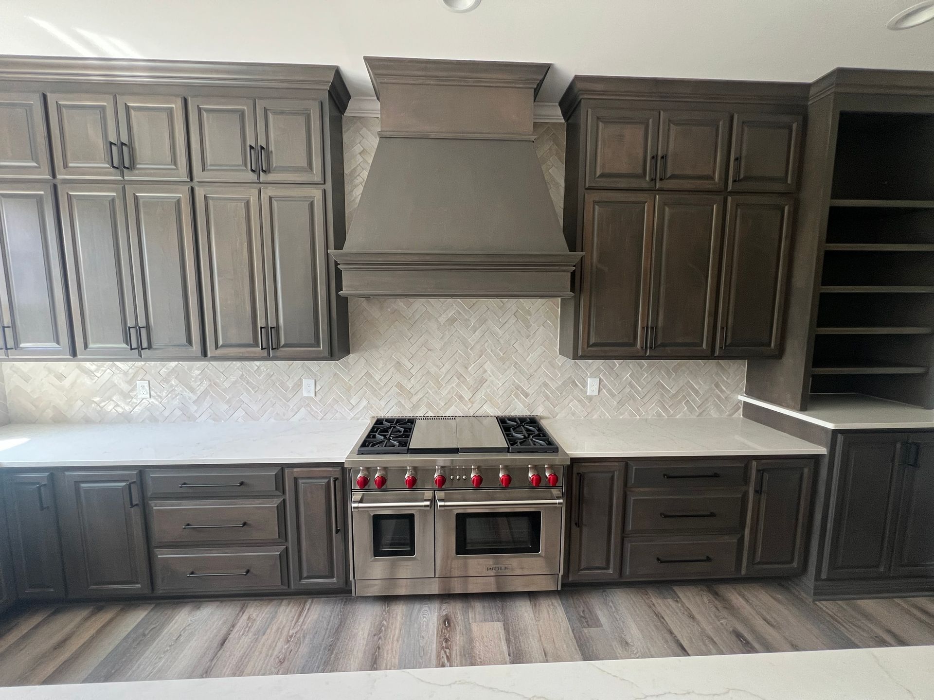 Kitchen with dark wood cabinets, stainless steel stove, and light backsplash.