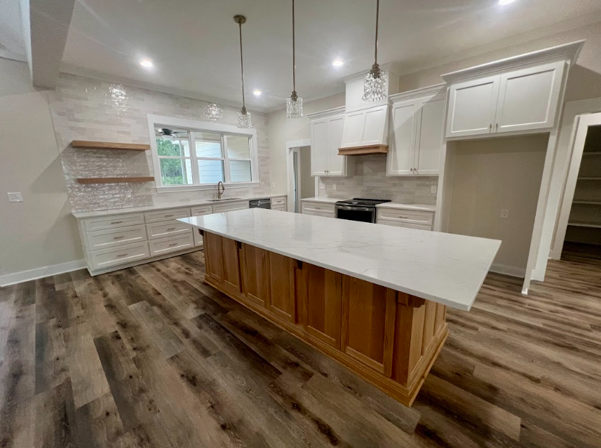 Modern kitchen with white cabinets, wooden island, and tile backsplash.