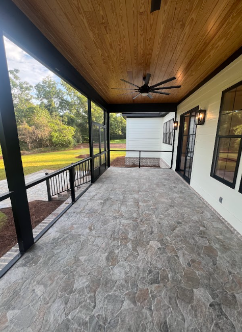 Screened-in porch with flagstone floor, black trim, wood ceiling, and a view of a grassy yard.