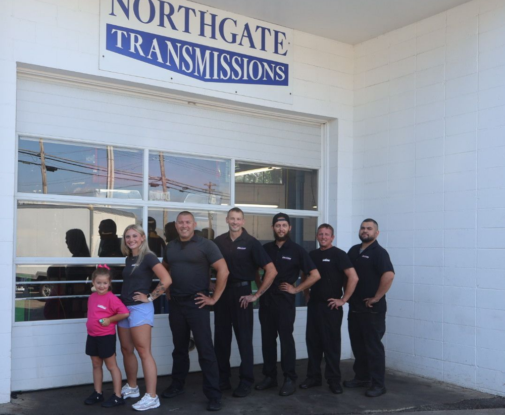 Northgate Transmissions shop staff posing in front of the garage door; blue sign.