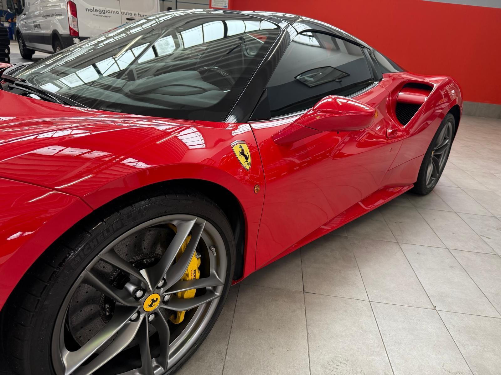 Auto sportiva Ferrari rossa con tetto nero, pinze dei freni gialle e logo laterale.