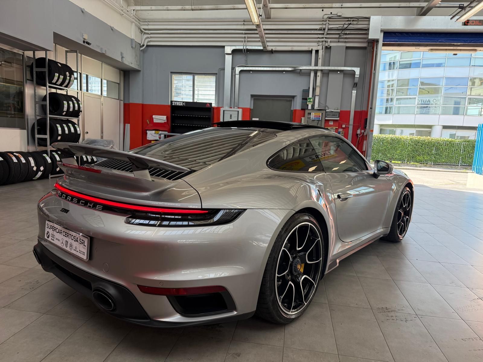 Porsche 911 Turbo S argentata in un garage, con la parte posteriore e laterale in mostra.