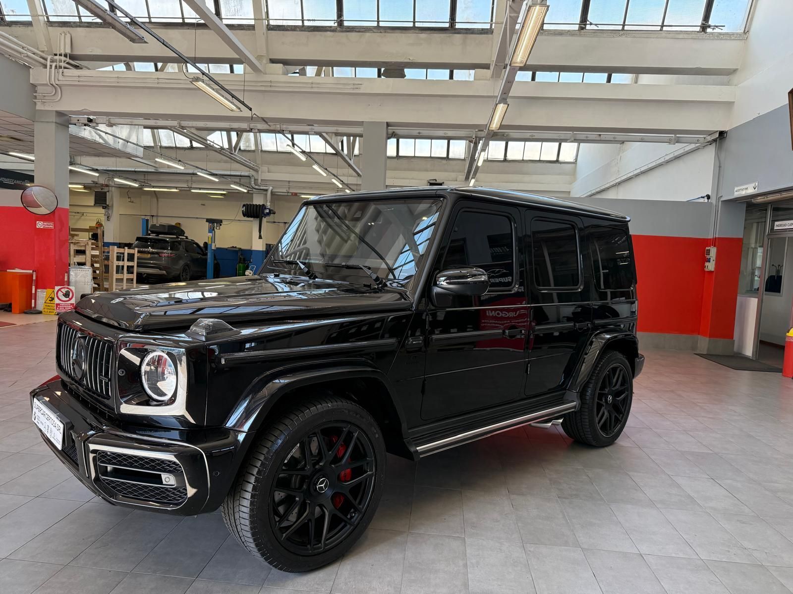 SUV Mercedes-Benz Classe G nero parcheggiato in un garage. Cerchi neri con dettagli rossi.