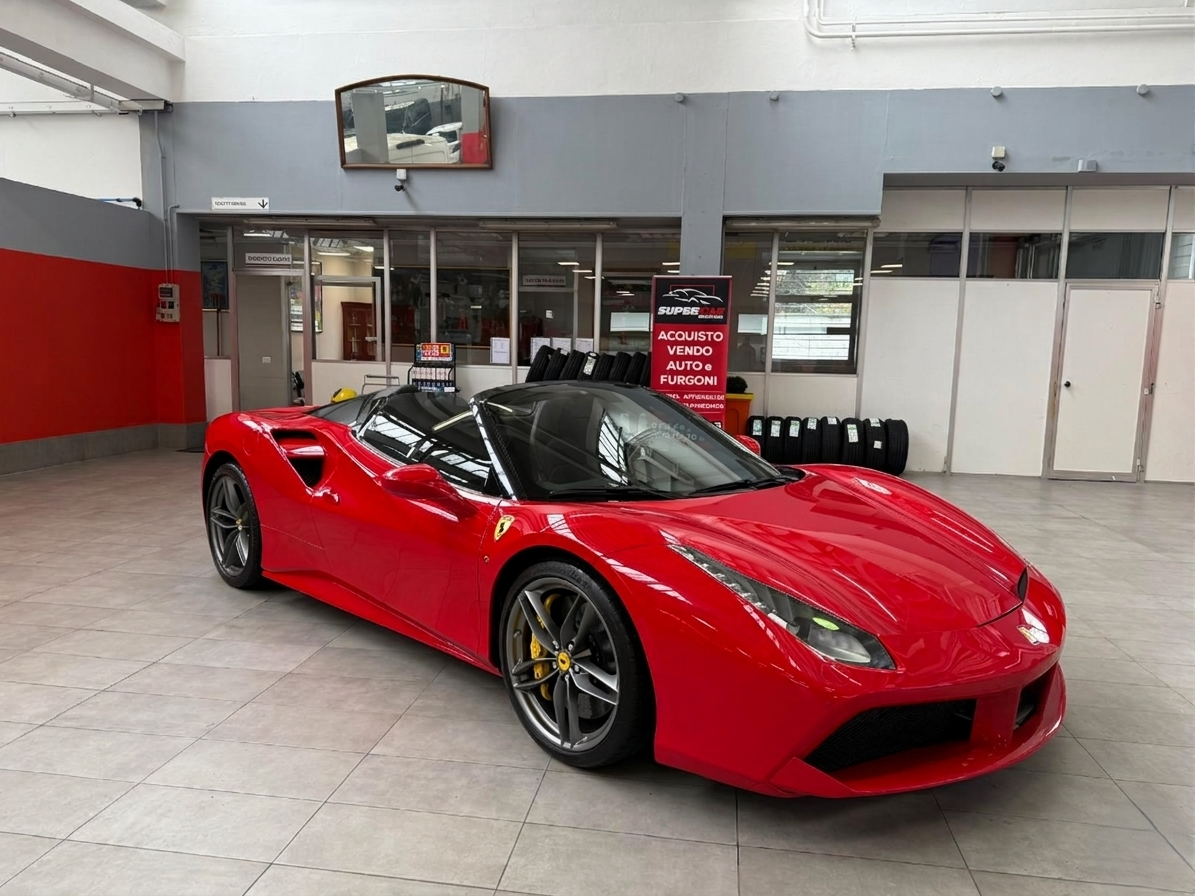 Ferrari rossa decappottabile parcheggiata in un garage, con capote scoperta, interni neri e pinze dei freni dorate.