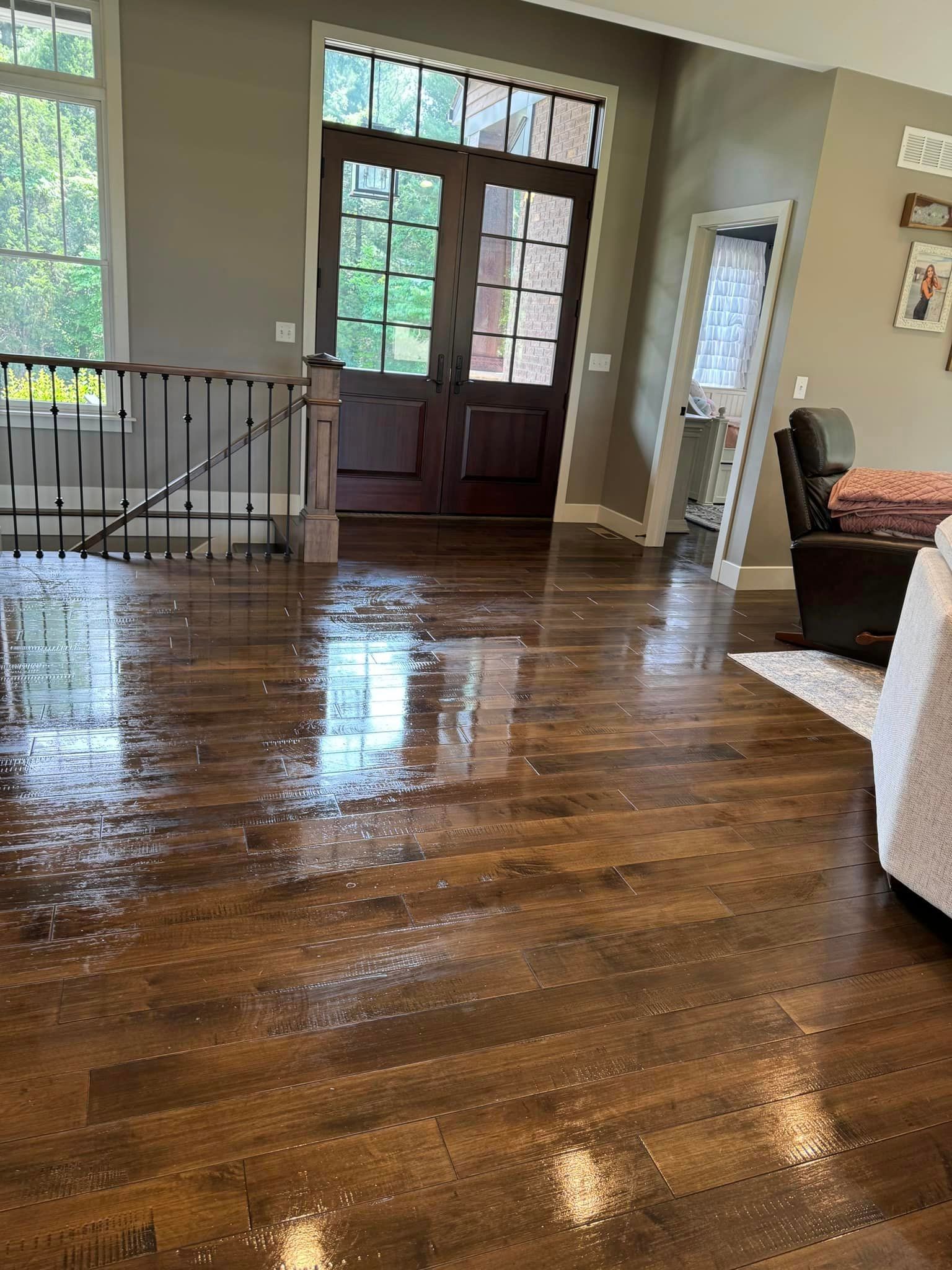 A living room with hardwood floors and a staircase leading to the second floor.