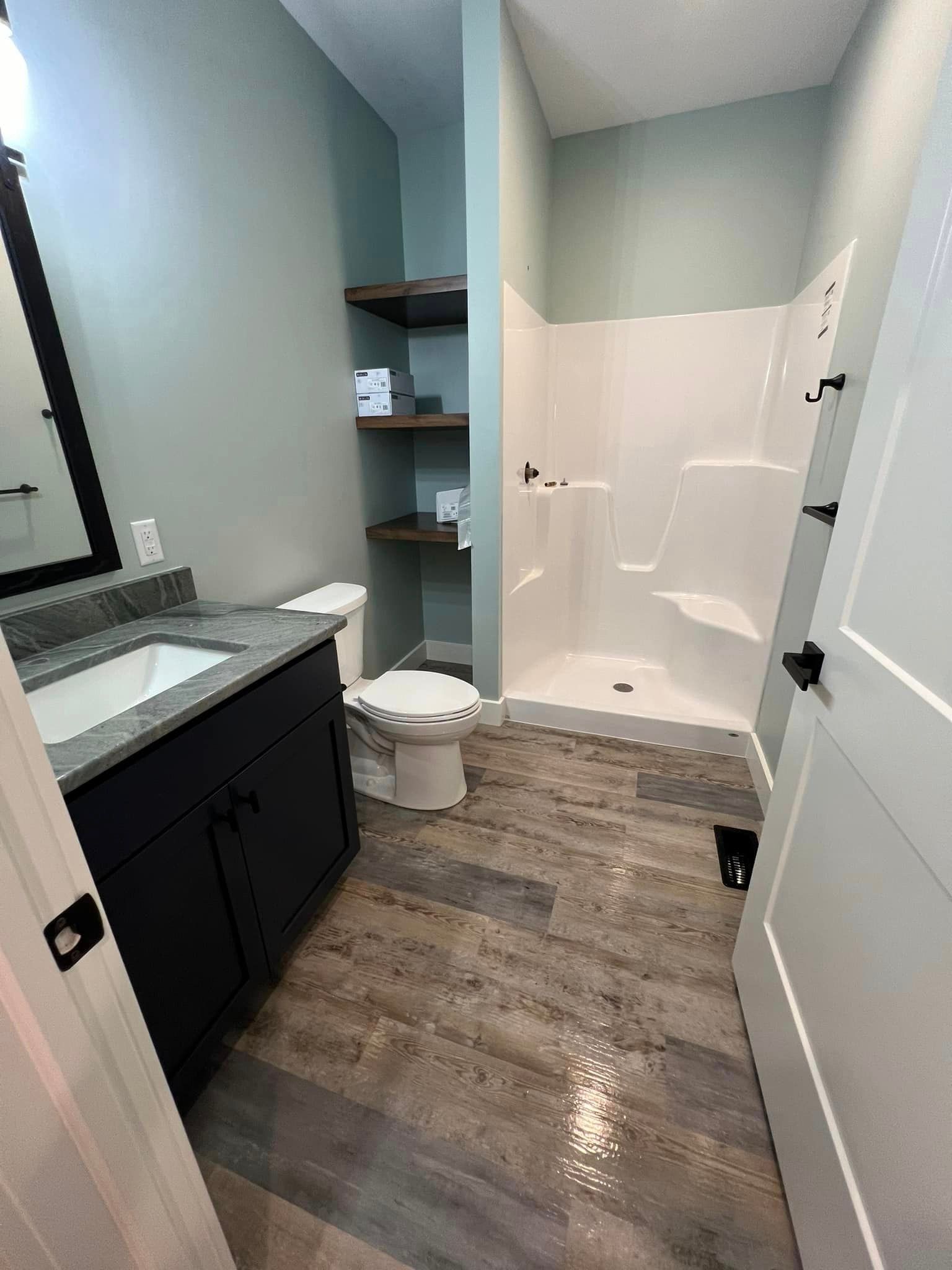 A bathroom with a toilet , sink and shower.