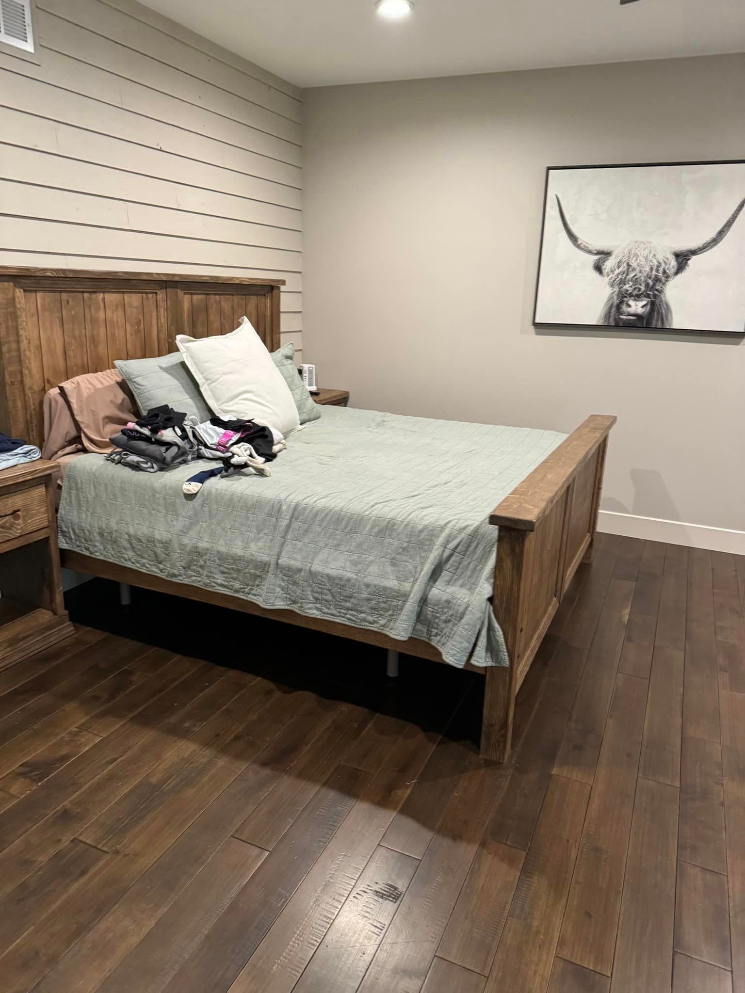 A bedroom with a bed , nightstand , and a painting on the wall.