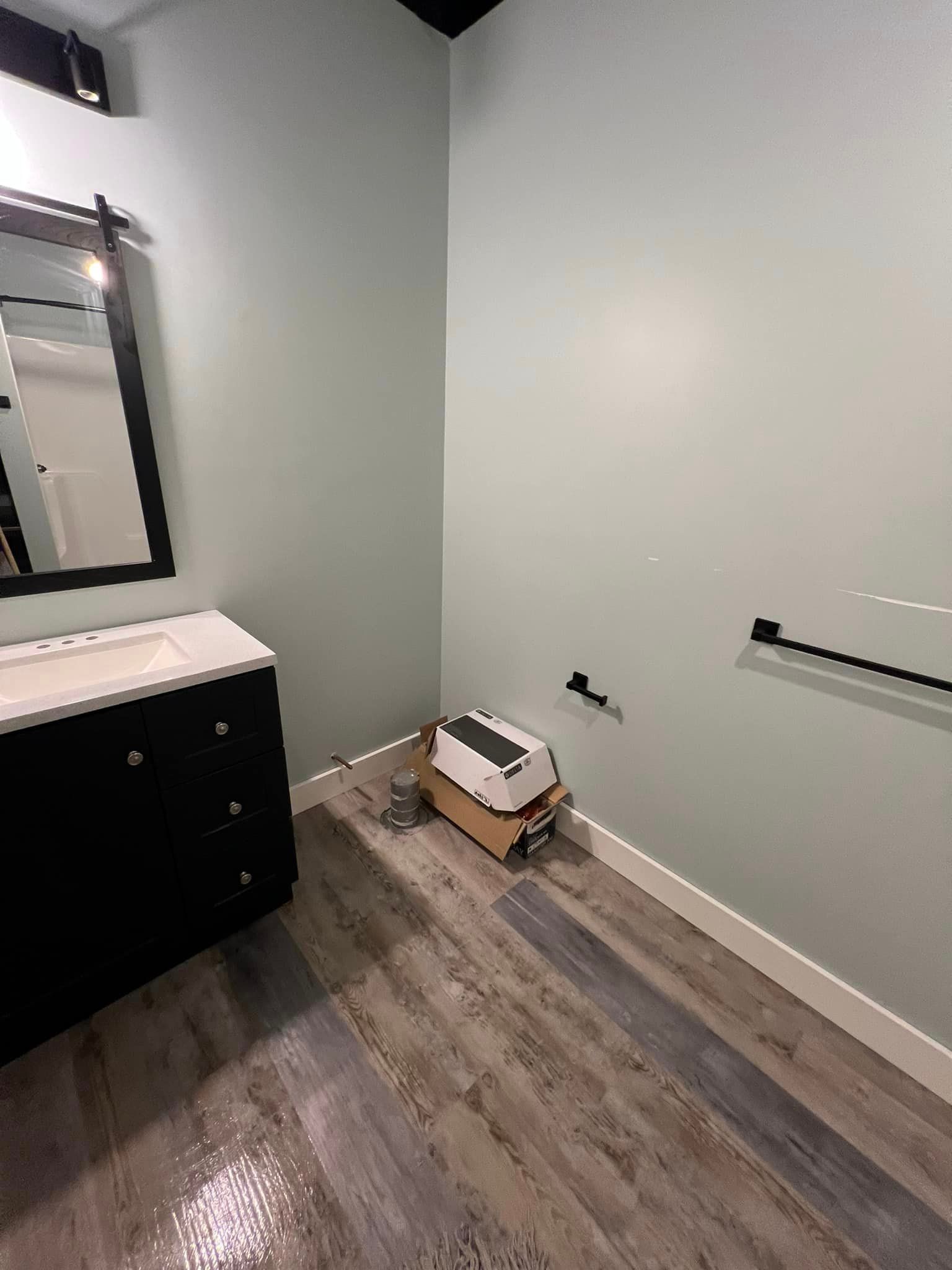 A bathroom with a sink , mirror , and wooden floor.
