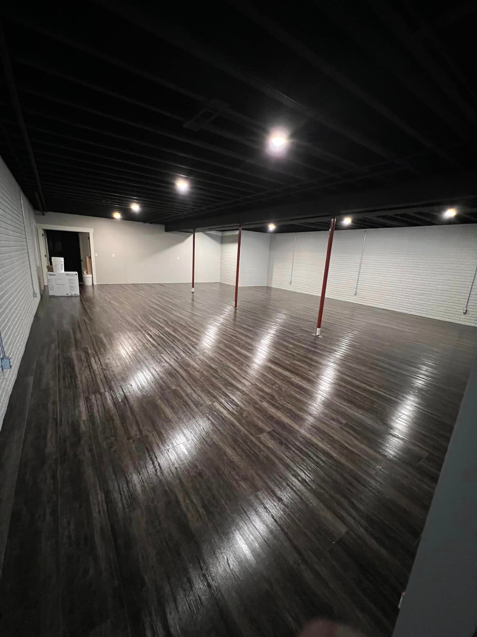 A large empty room with a wooden floor and a black ceiling.