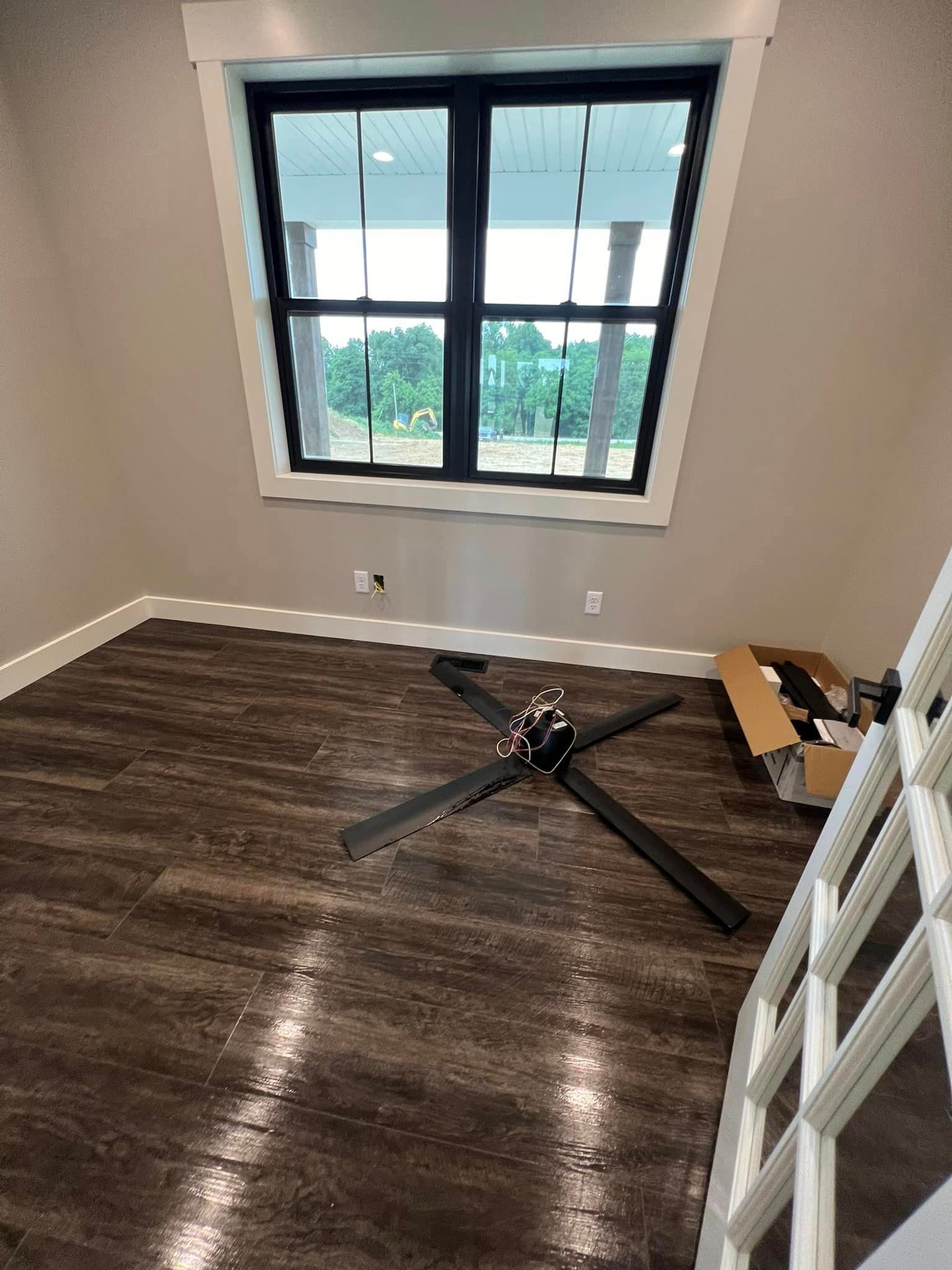 An empty room with a ceiling fan and a window.