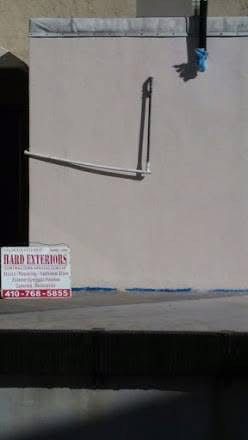 A light-colored wall with a plumbing pipe. A business sign at the bottom.