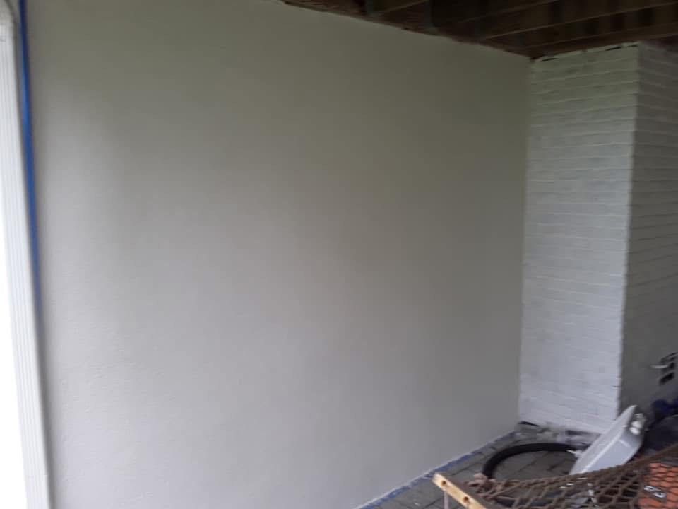 White-painted wall with a white brick chimney in an outdoor setting; blue painter's tape visible.