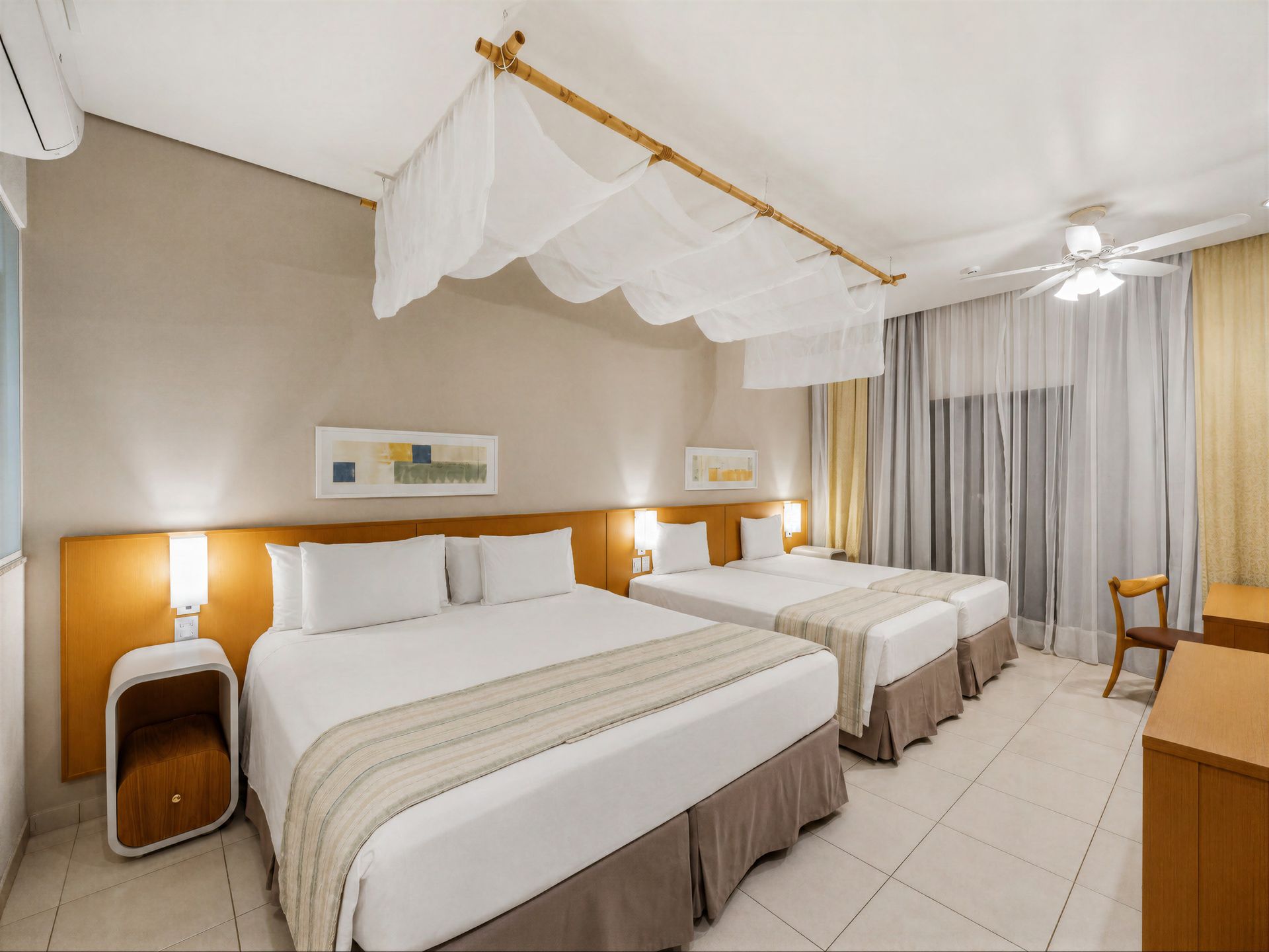 Um quarto de hotel com duas camas, uma escrivaninha e uma televisão.