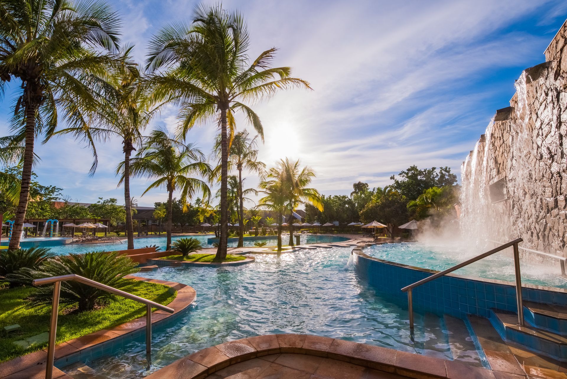 Uma grande piscina cercada por palmeiras e uma cachoeira.