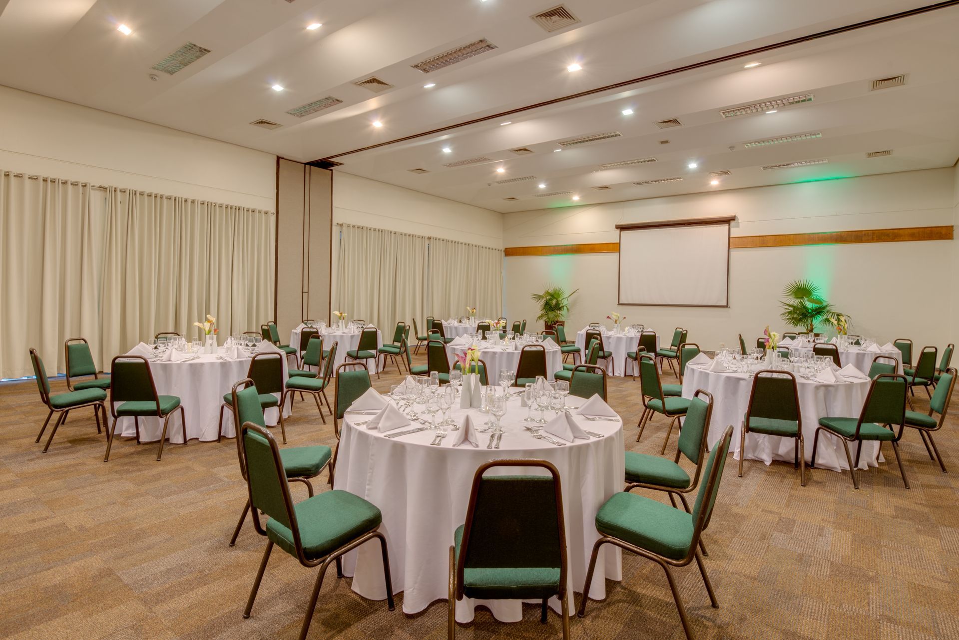 Uma grande sala com mesas e cadeiras preparadas para um banquete.