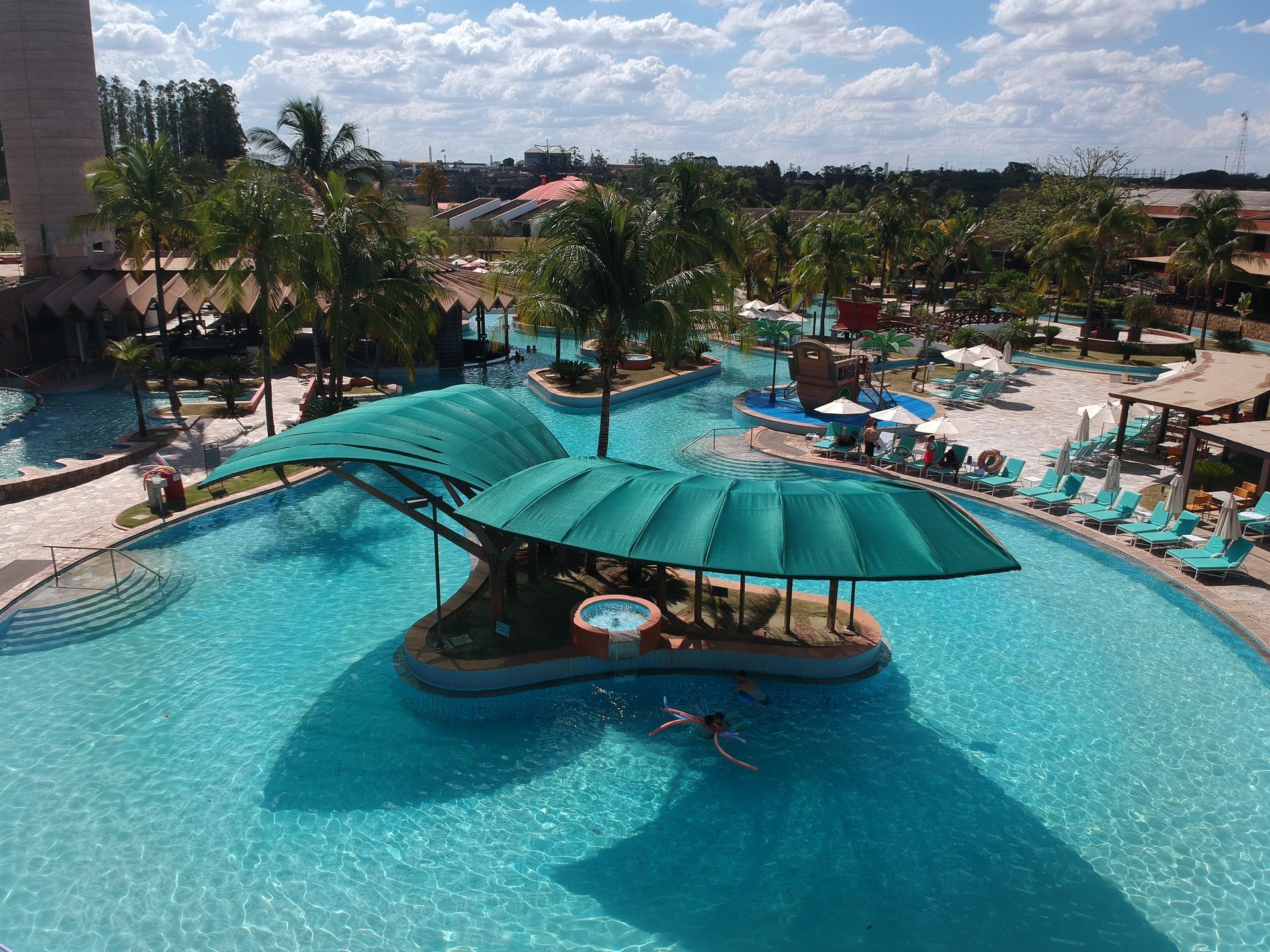 Uma vista aérea de uma grande piscina com um guarda-sol verde.
