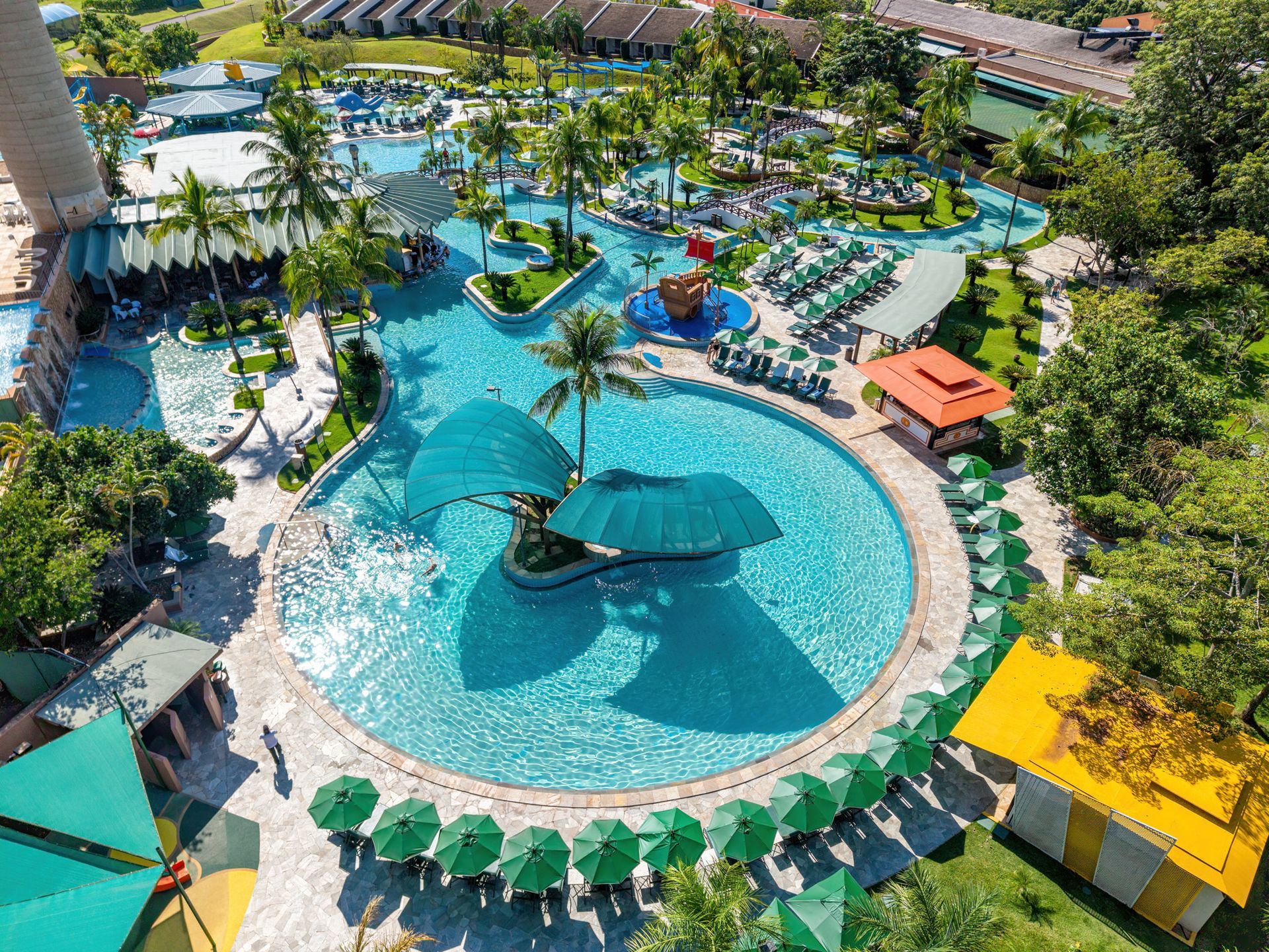 Uma grande piscina com um bar no meio, cercada por palmeiras.