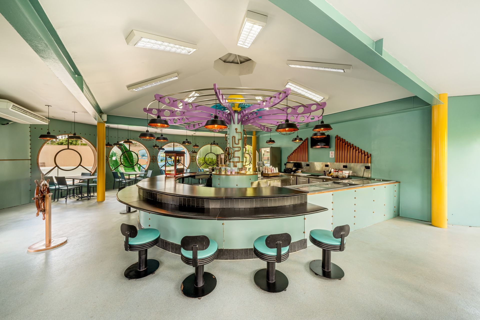 Um restaurante com mesas e cadeiras e um poste amarelo no meio.