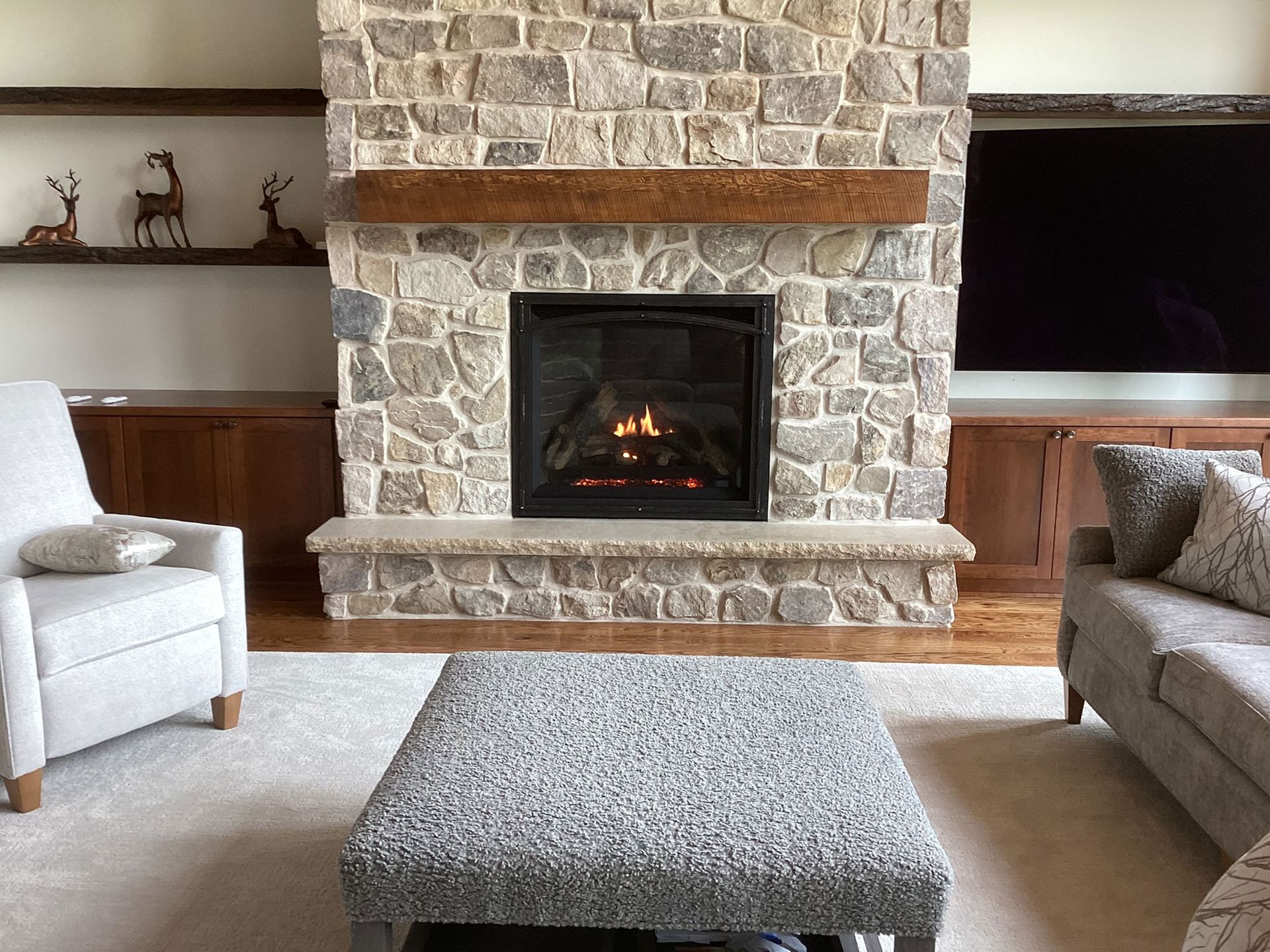 Living room with stone fireplace, wooden mantel, and a lit fire.