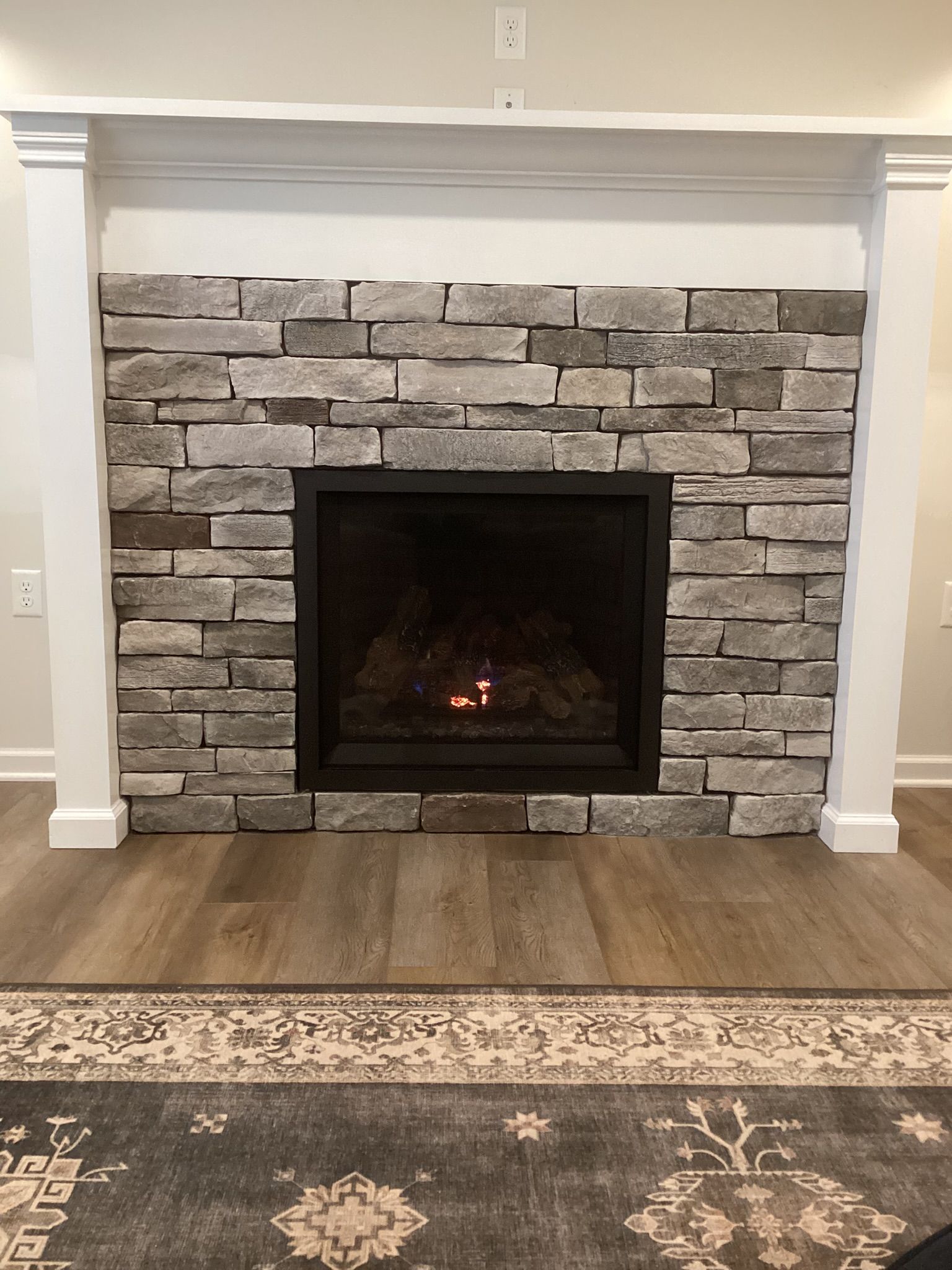 Fireplace with stone surround, white mantel, and a burning fire.