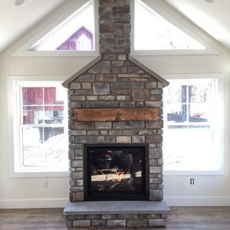 Stone fireplace with a wooden beam, flanked by windows with a gable window above.
