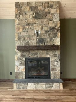 Stone fireplace with a dark wood mantle. The wall behind the fireplace is green.