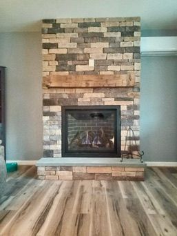 Fireplace with brick facade, wooden mantel, and glass firebox in a living room.