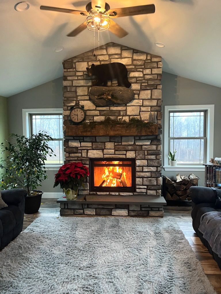 Cozy living room with stone fireplace, bear carving, lit fire, and Christmas decor.