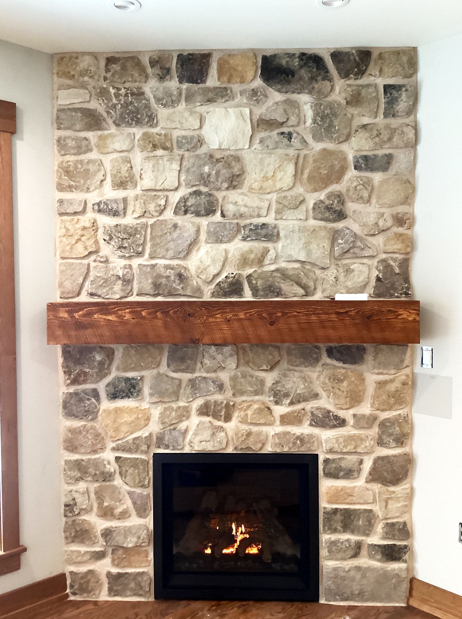 Stone fireplace with a wooden mantel, flames in the hearth.