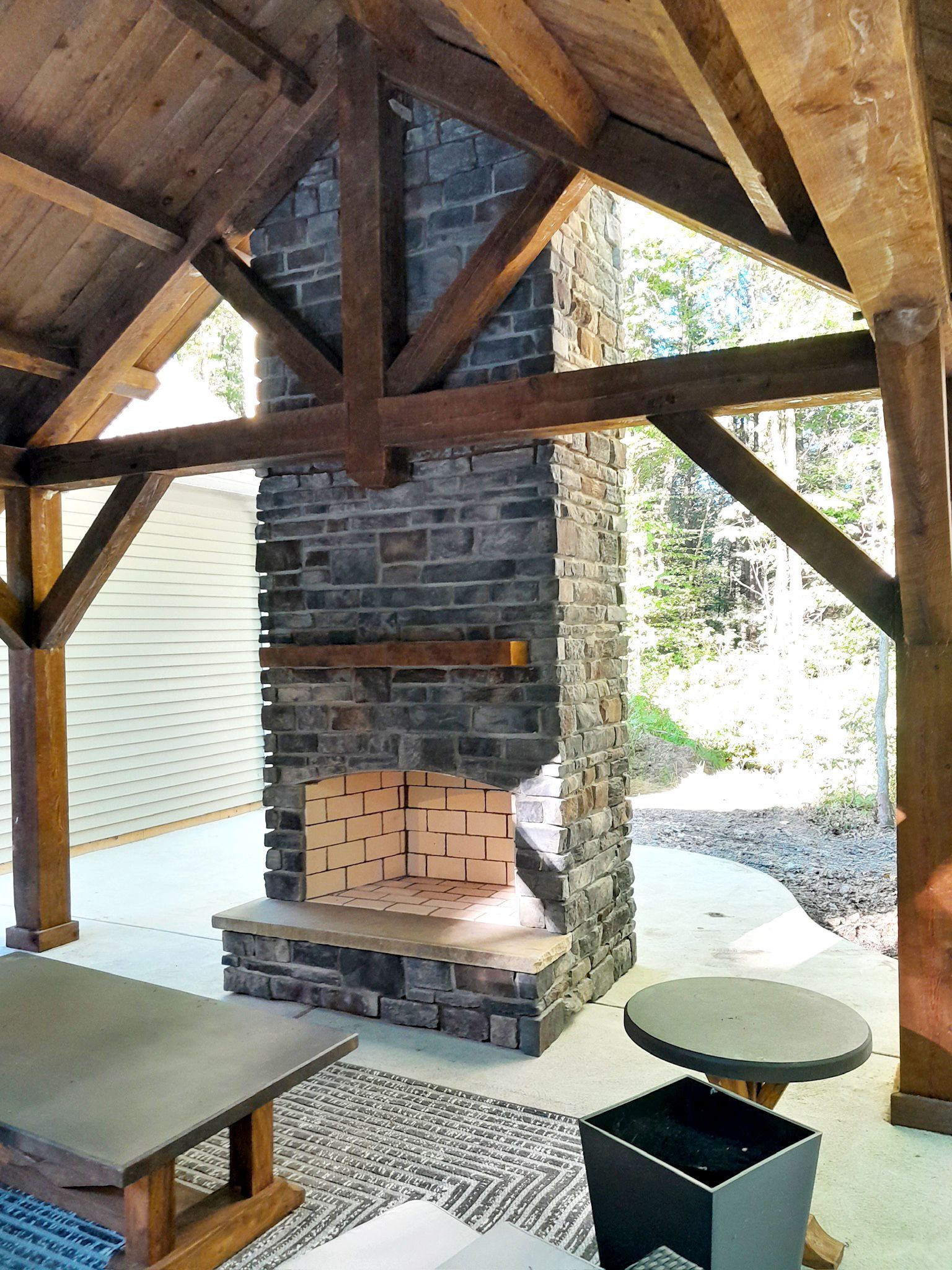 Stone fireplace in a wooden pavilion with outdoor seating.