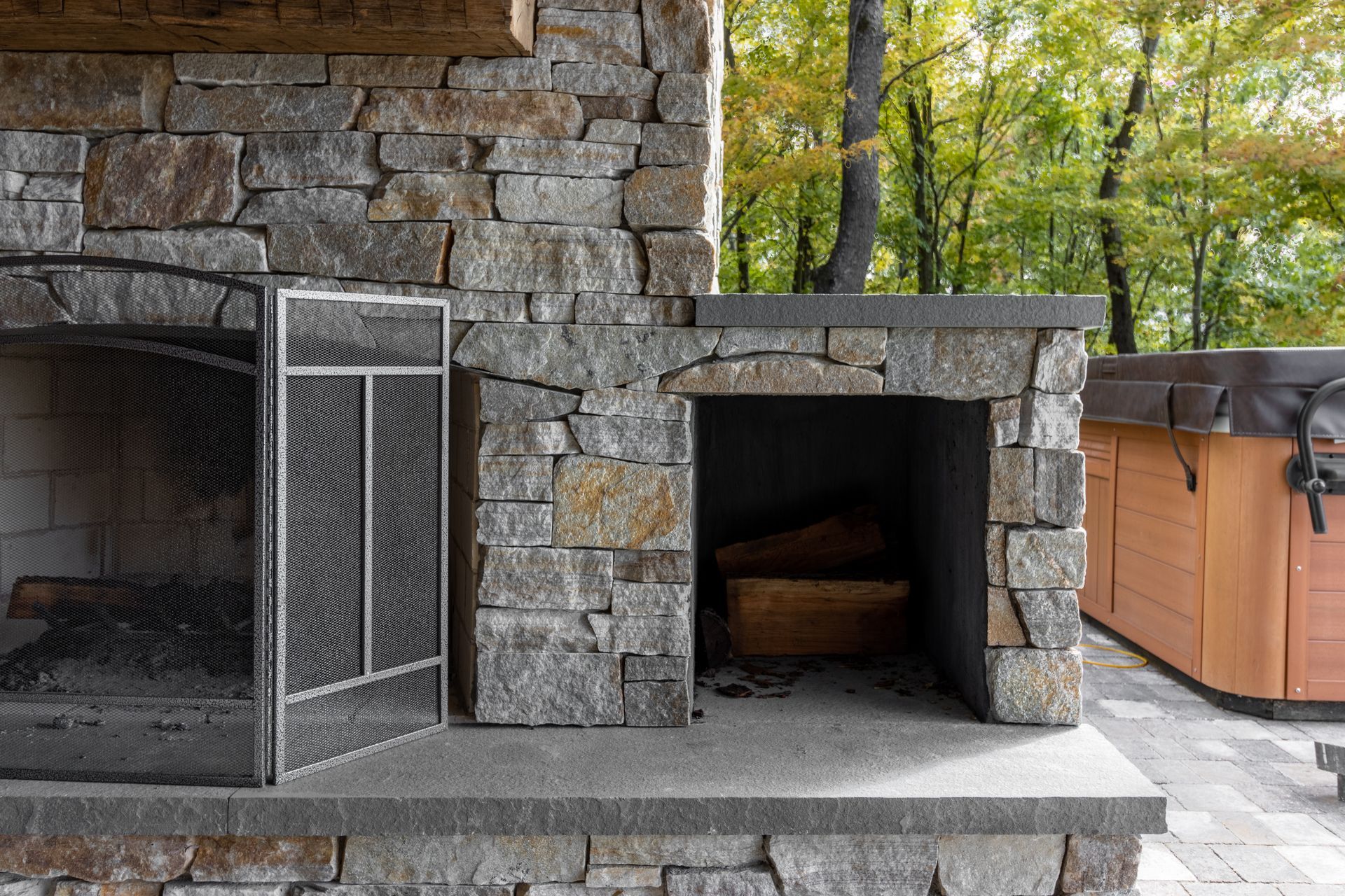 A stone fireplace with a screen on the side of it.