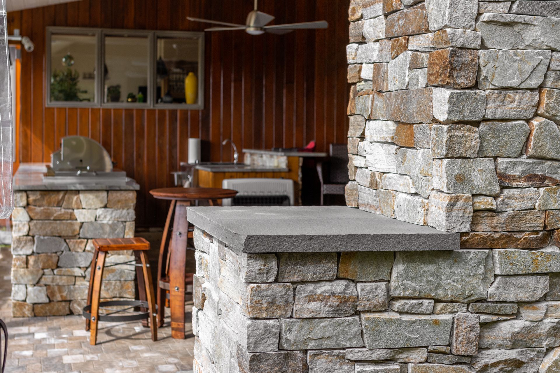 A kitchen with a stone wall and a ceiling fan.