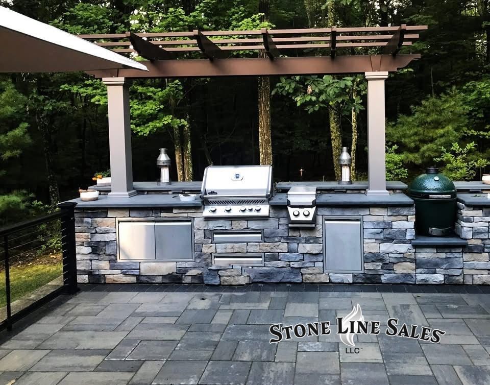Outdoor kitchen with grill, Big Green Egg, and pergola, built with stone and stainless steel.