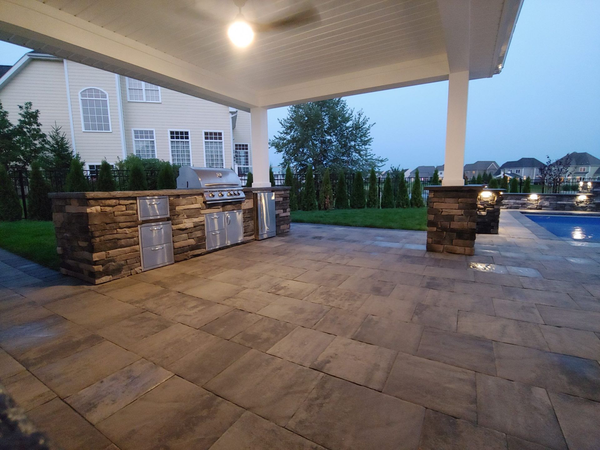 A patio with a ceiling fan and a swimming pool in the background