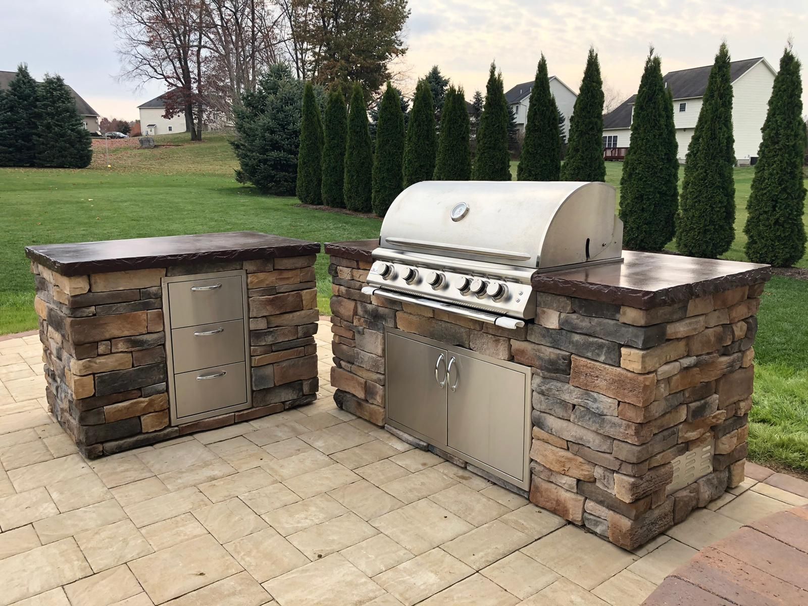 A stainless steel grill is sitting on top of a stone counter.