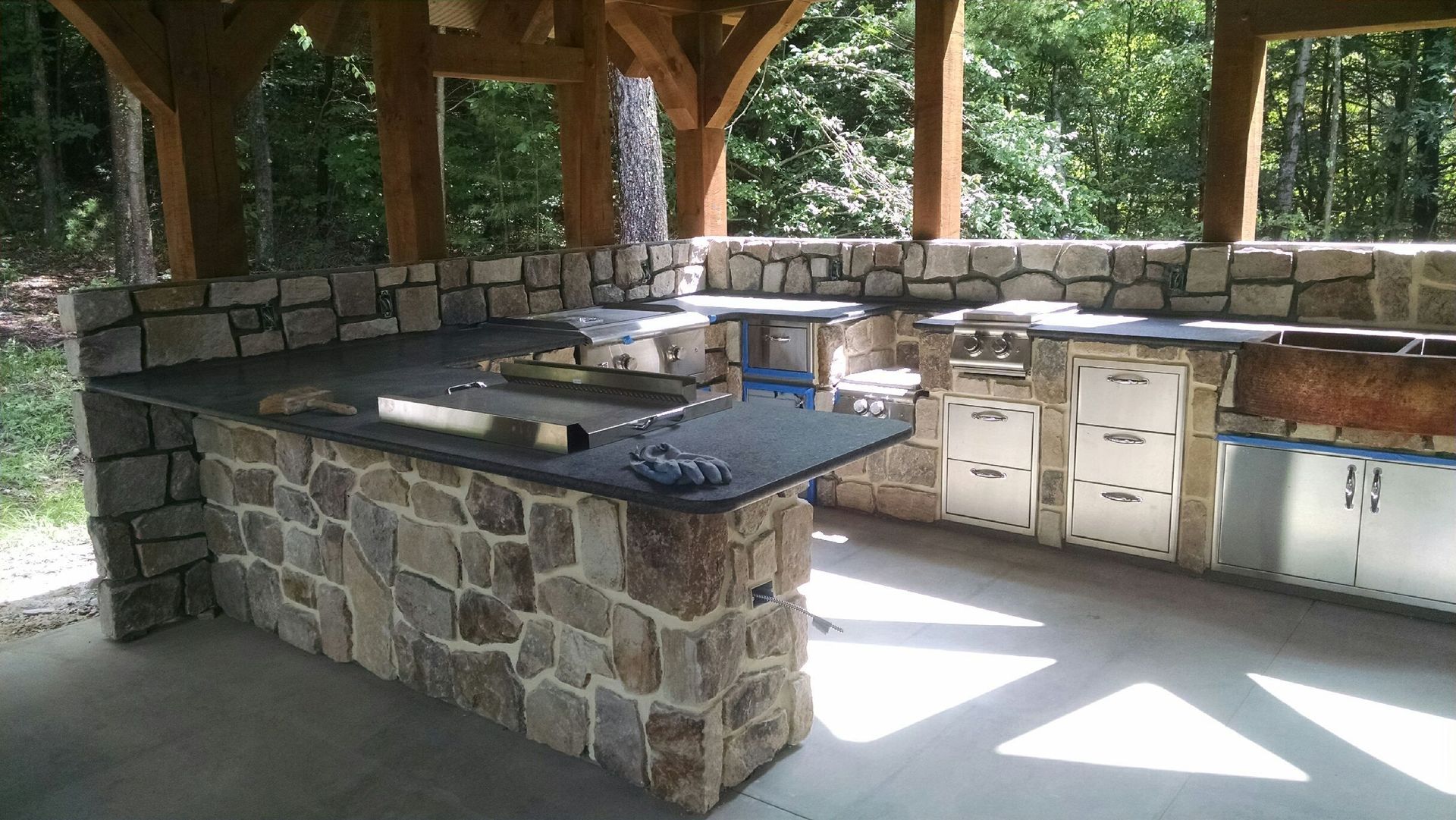 A large stone kitchen with a wooden structure surrounding it