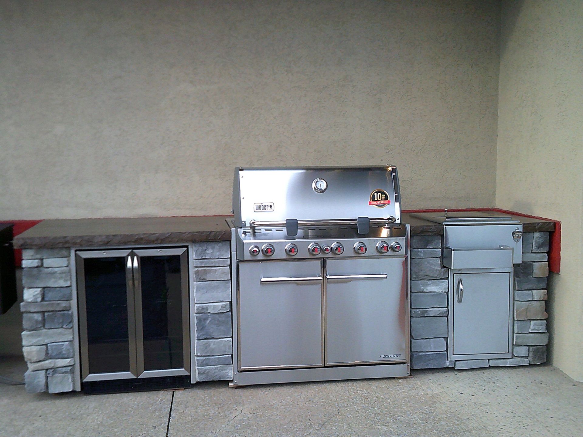 An outdoor kitchen with a stainless steel grill