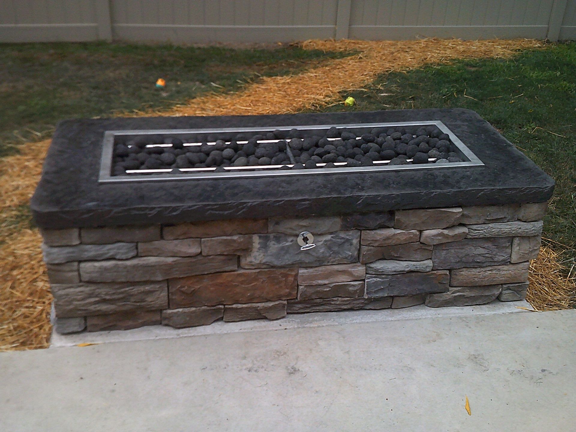 A fire pit made of stone is sitting on top of a concrete patio.
