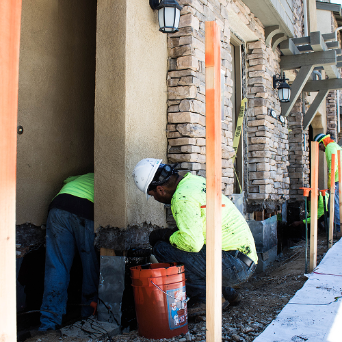 Construction workers installing stone veneer on a building exterior.