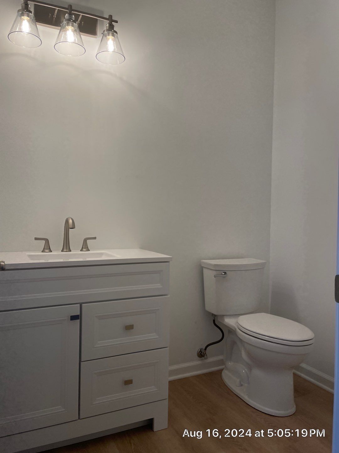 A bathroom with a sink , toilet , and light fixture.