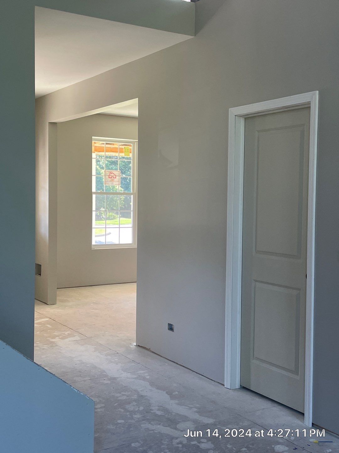 A hallway with a door and a window in a house under construction.
